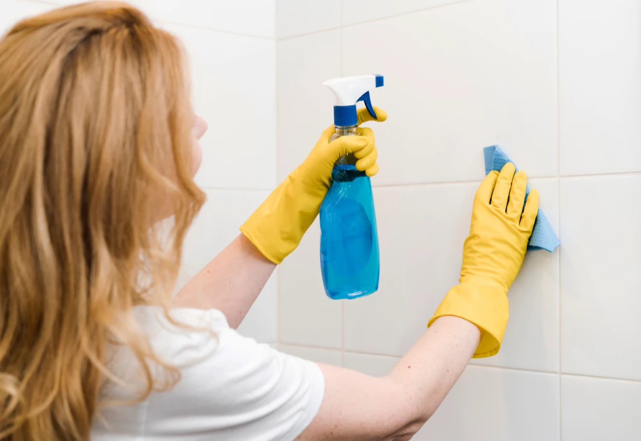 Vrouw maakt badkamer tegels schoon met spuit en doekje